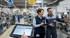 Zwei Techniker mit Tablet im Gespräch neben einer Maschine in einer Produktionshalle.
