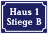Blaues Schild mit weißem Rahmen und Text "Haus 1 Stiege B".