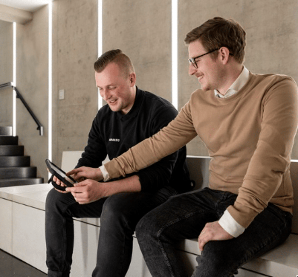 Zwei Kollegen arbeiten gemeinsam an einem Tablet