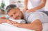 Mann mit geschlossenen Augen, der eine Rückenmassage von einer Therapeutin erhält.