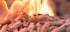 Holzpellets mit brennenden Flammen im Hintergrund.
