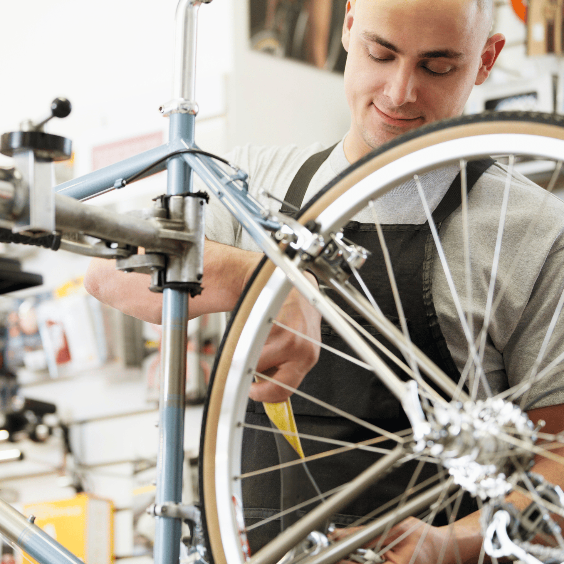 Ein Fahrradmechaniker mit schwarzer Schürze repariert ein Rennrad in einer Werkstatt