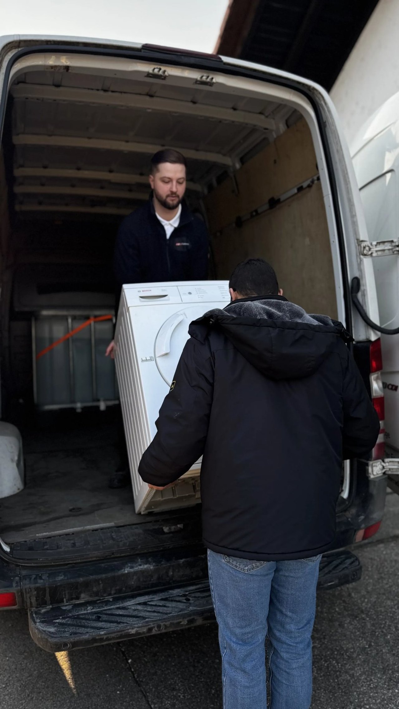 Team von GlanzGurus lädt bei einer Entrümpelung einen Trockner in den Transporter