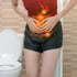 A woman in pain clutches her stomach, showing gut issues.
