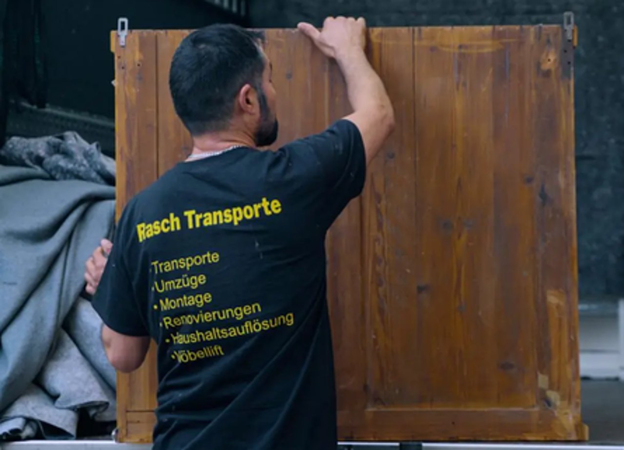 Mitarbeiter von Rasch Transporte trägt eine Holzplatte in den Umzugswagen
