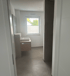 Modernes Badezimmer mit Waschbeckenunterschrank, rechteckigem Waschbecken, Spiegel und Fenster mit Jalousien.