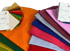 Bunte Stoffmuster und ein Farbfächer für die Farbberatung mit dem Logo von Haar Atelier auf schwarzem Hintergrund.