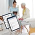 Eine Physiotherapeutin zeigt einer Patientin Übungen auf einem Tablet, während sie auf einer Untersuchungsliege sitzt.
