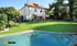 Großes weißes Haus mit rotem Dach, gr ünem Rasen und Swimmingpool im Vordergrund.