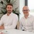 Die Geschäftsführer von OV Solutions am Bürotisch sitzend Marcel Medved und Artur Belov