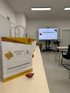 Weiße Papiertüten mit „Mission Kita“ Logo und Text „Dein Start in eine erfolgreiche Weiterbildung“ auf Holztischen.
