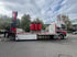 Ein Heavy-Lkw mit Kranarm transportiert drei große rote Industrietransformatoren auf seiner Ladefläche.