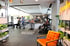 Fitnessstudio mit mehreren Personen, die an verschiedenen Geräten trainieren, und einem orangefarbenen Sessel im Vordergrund.