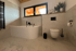 Modernes Badezimmer mit freistehender Badewanne, Toilette und Fliesen in Marmoroptik.