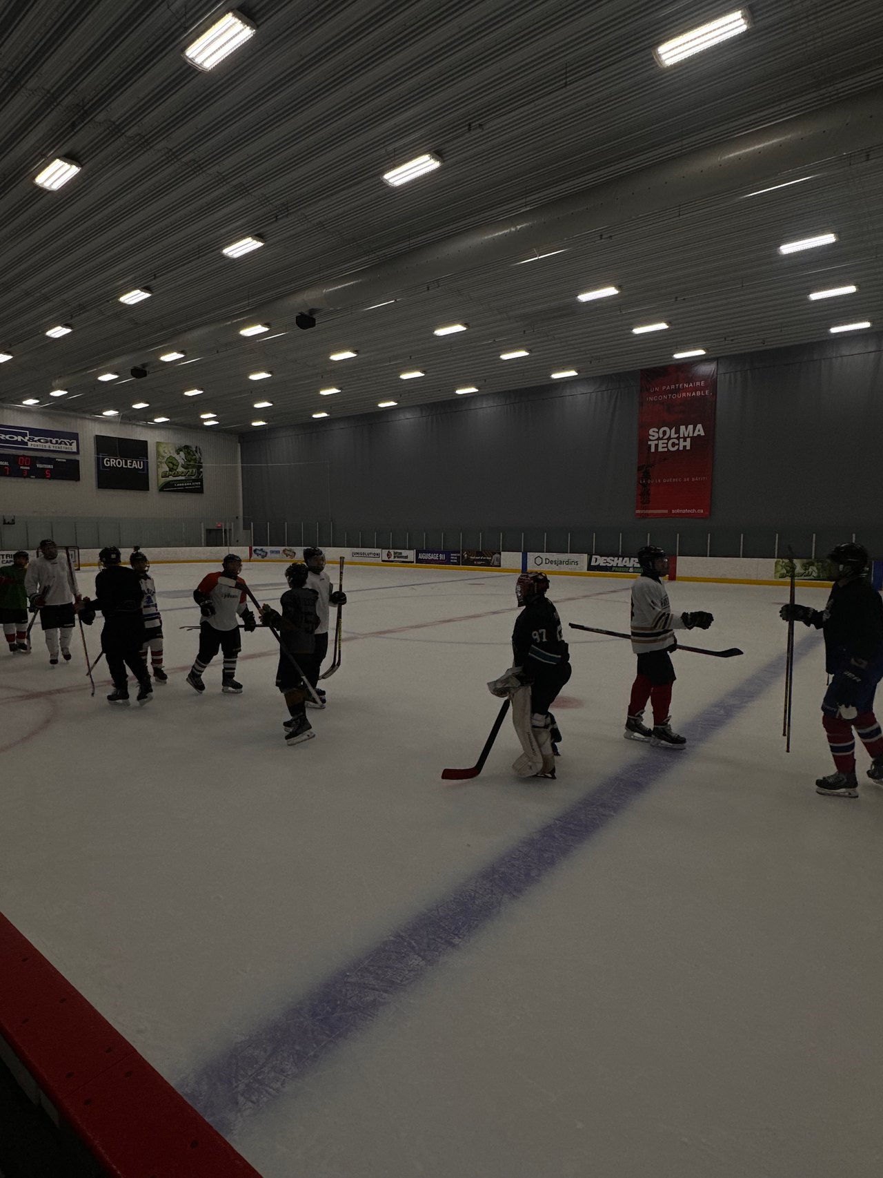 Des joueurs de hockey rassemblés sur la patinoire, bâtons à la main