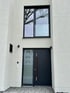 Moderne Haustür und Seitenfenster mit Hausnummer 18 in weißer Fassade.