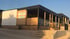Ein modernes Haus mit Holzverkleidung, Terrasse und der Aufschrift "3V HOLIDAY RESORT Villa Mojito" an der Seite.