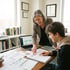 A female teacher points to ACT test data charts on a desk while reviewing results with a male student in a bright office.