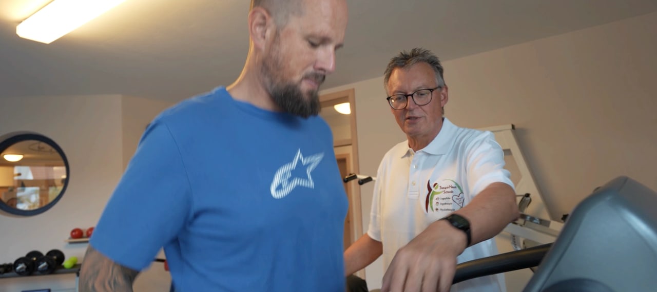 Therapeut begleitet einen Mann beim Training auf einem Laufband
