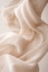 Helle, durchscheinende Stoffbahnen in Beige und Off-White schweben und falten sich.