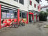 Eingang zum Nahkauf-Supermarkt mit Fahrrädern und roten Fensterrahmen.
