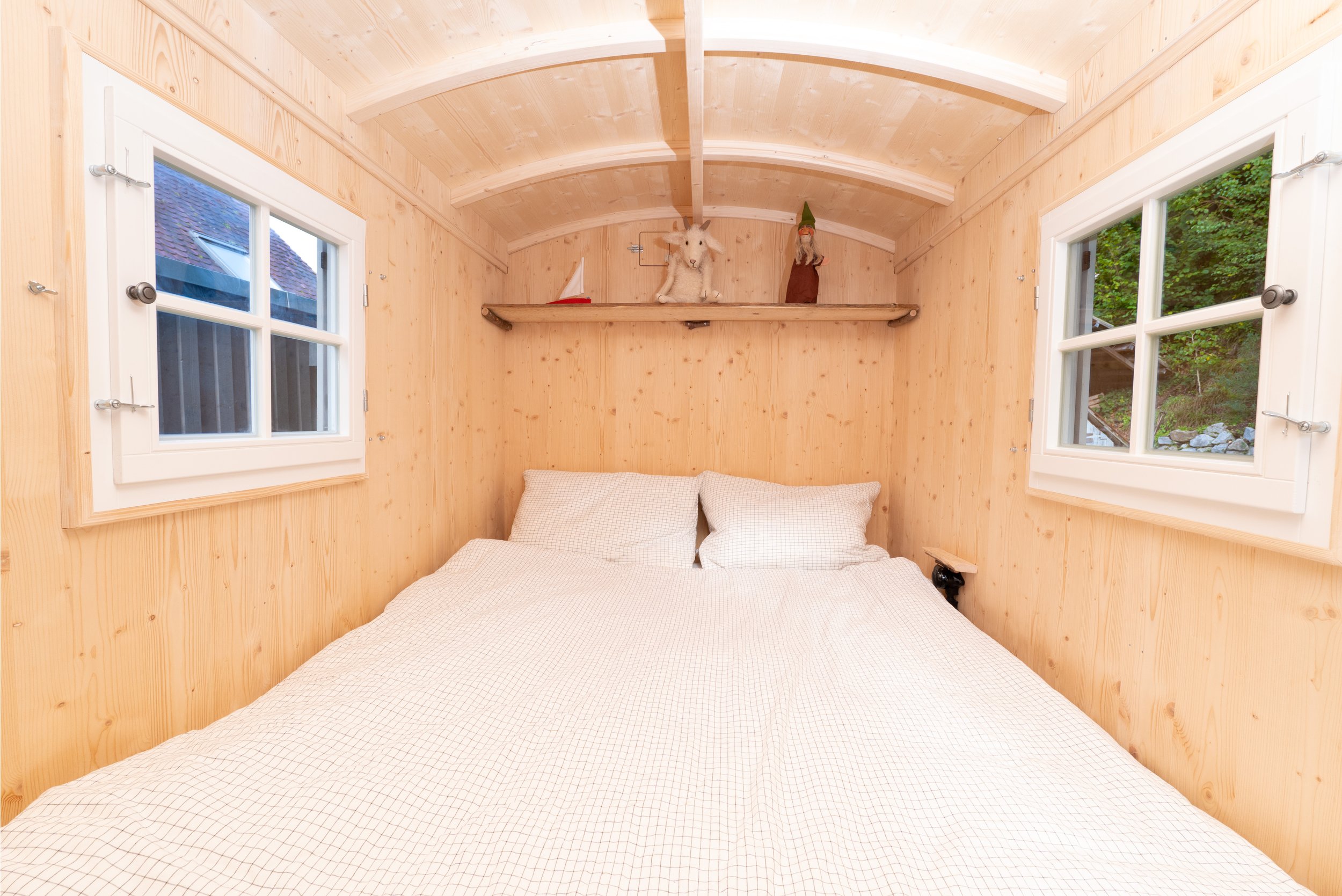 Innenraum des Zirkuswagens mit Doppelbett und Holzverkleidung