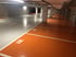Leere Tiefgarage mit orangefarbenen und grauen Parkplätzen, nummeriert 180 und 181.
