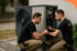 Zwei Männer in schwarzen T-Shirts und beigefarbenen Hosen reparieren eine Wärmepumpe im Freien.