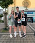 Drei Läufer mit Startnummern und Medaillen zeigen nach einem Rennen am Paderborn Lippstadt Airport den Daumen nach oben.