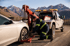 Towing Sandy operator securing a sedan to a tow truck on a mountain roadside for vehicle recovery service.