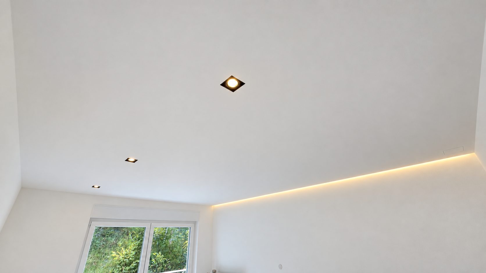Abgehängte Gipskartondecke mit Einbauspots und indirekter Lichtfuge in einem Wohnraum