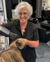Friseursalon mit zwei Friseurinnen, die Kundinnen die Haare schneiden und frisieren.