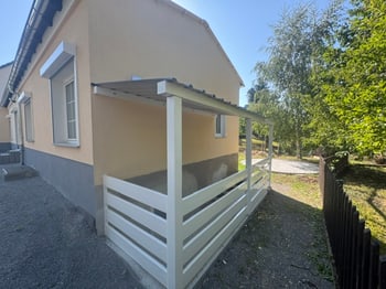 Überdachter Terrassenbereich mit weißem Geländer an der Hausseite