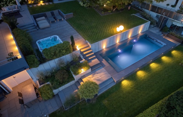 Beleuchtete Poolanlage mit Terrasse bei Nacht, realisiert von POOL+HOME im Großraum Stuttgart