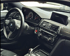 Interieur eines BMW M4 mit Lenkrad, Armaturenbrett, Infotainment-Bildschirm und Gangschaltung.