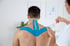 A man is being treated with kinesiology taping therapy on his back