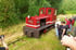 Rote Schmalspurbahnlokomotive "Doris" auf Gras neben den Gleisen, Passagiere fotografieren.