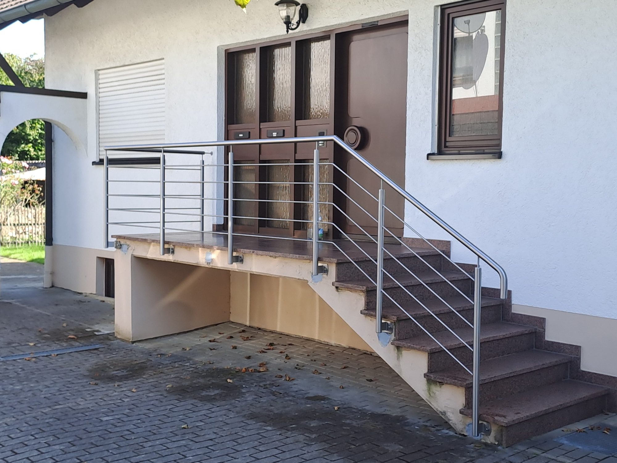 Edelstahl-Treppengeländer mit waagerechten Querstäben und Handlauf an einer Eingangstreppe aus Granit