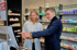 Apothekerin im weißen Kittel und Mann im blauen Sakko betrachten gemeinsam einen Monitor in einer Apotheke.