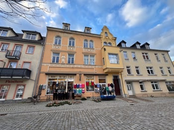 Frontansicht des Wohn- und Geschäftshauses mit Fassadenschmuck und Blumenladen im Erdgeschoss