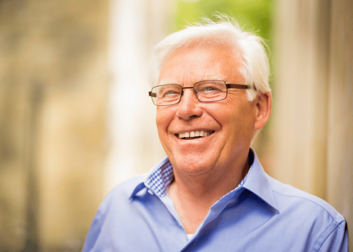 Älterer Patient lächelt unbeschwert mit festen Zähnen