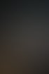 Drei junge Männer besprechen gemeinsam Inhalte auf einem Laptop in einem modern eingerichteten Büro mit dunkler Wand.