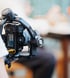 A camera mounted on a black gimbal stabilizer with "CRANE" visible on the side, held by a person.