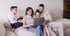 Familie mit zwei Kindern sitzt gemeinsam auf dem Sofa und plant am Laptop ihr Familienbudget.