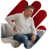 A man on a couch grips his back, seeking pinched nerve treatment.