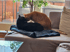 Eine schwarze Katze und eine rote Katze sitzen zusammen auf einem Sofa und berühren sich mit den Köpfen.