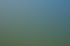 Fußballspieler in blauen und gelben Trainingsanzügen dribbeln einen Ball auf einem grünen Rasenplatz unter blauem Himmel.