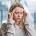A woman holds her head, experiencing a headache.







