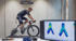 Ein Radfahrer führt bei gebioMized ein Bikefitting auf einem Rollentrainer durch, während ein Monitor Druckanalysen zeigt.