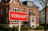 Rotes Schild mit der Aufschrift "VERKAUFT" vor einem Einfamilienhaus.